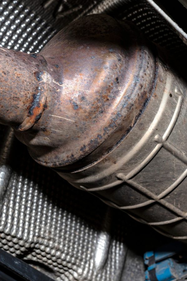 A diesel particulate filter in the exhaust system in a car on a lift in a car workshop, seen from below.
